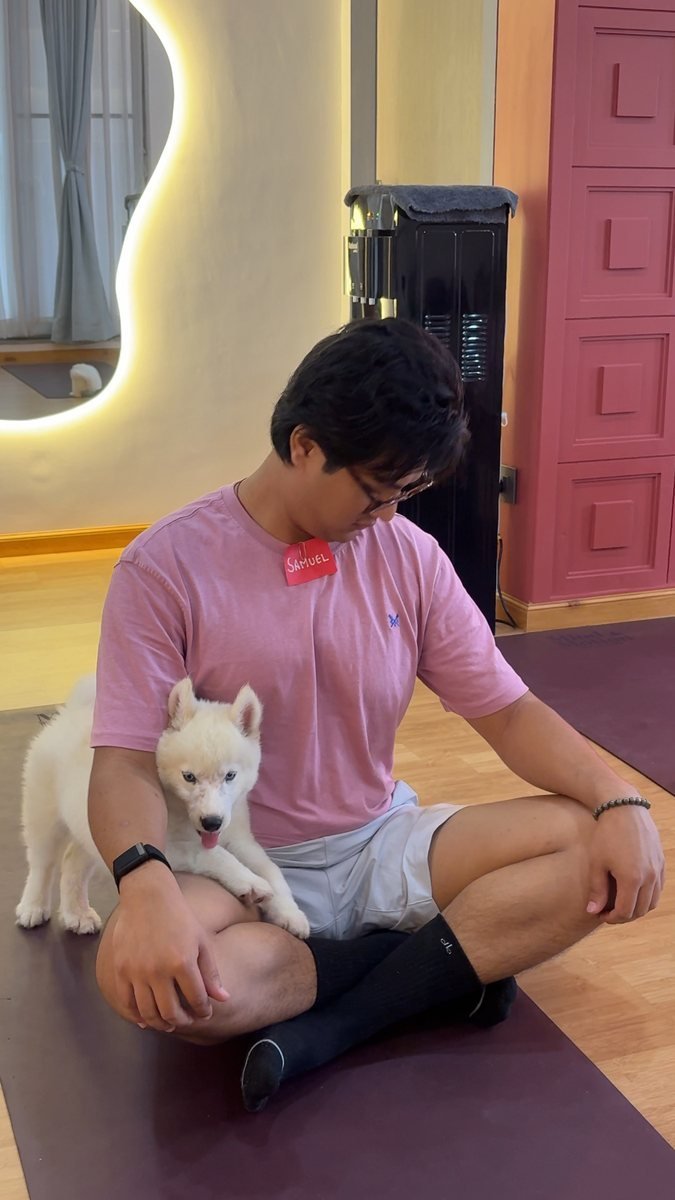 A guest sitting cross-legged with a husky puppy in his lap.