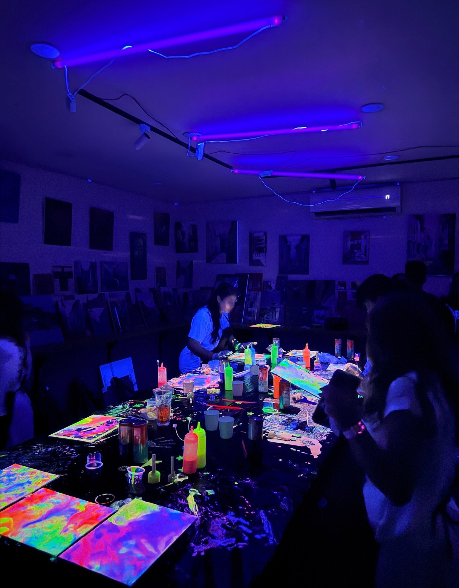 Participants painting with fluorescent colours under UV light.